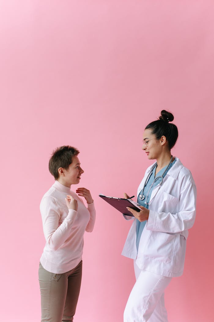 Services A doctor consults with a patient against a pink background, illustrating healthcare professionalism.